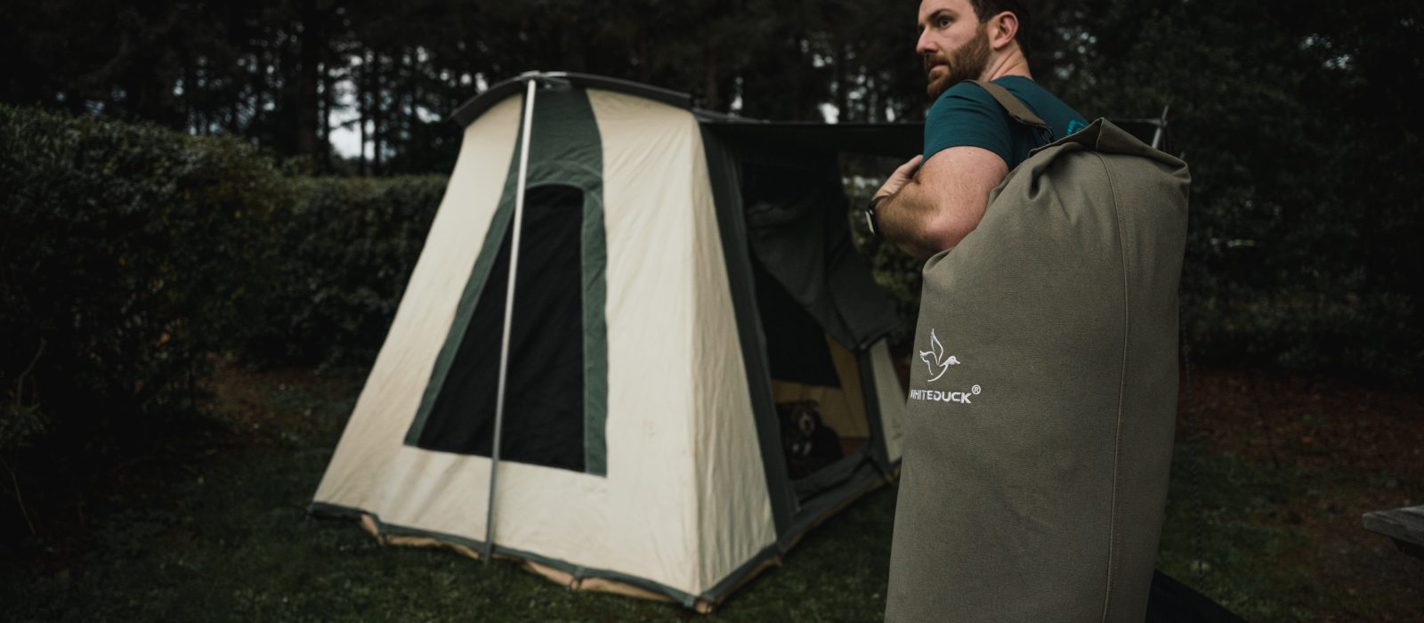 man with bell tent and canvas duffle bag for camping adventure
