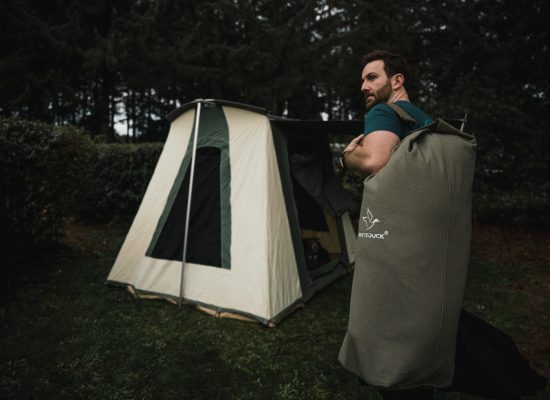 man with bell tent and canvas duffle bag for camping adventure