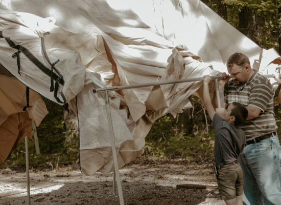 kids and father pitching a tent for family camping