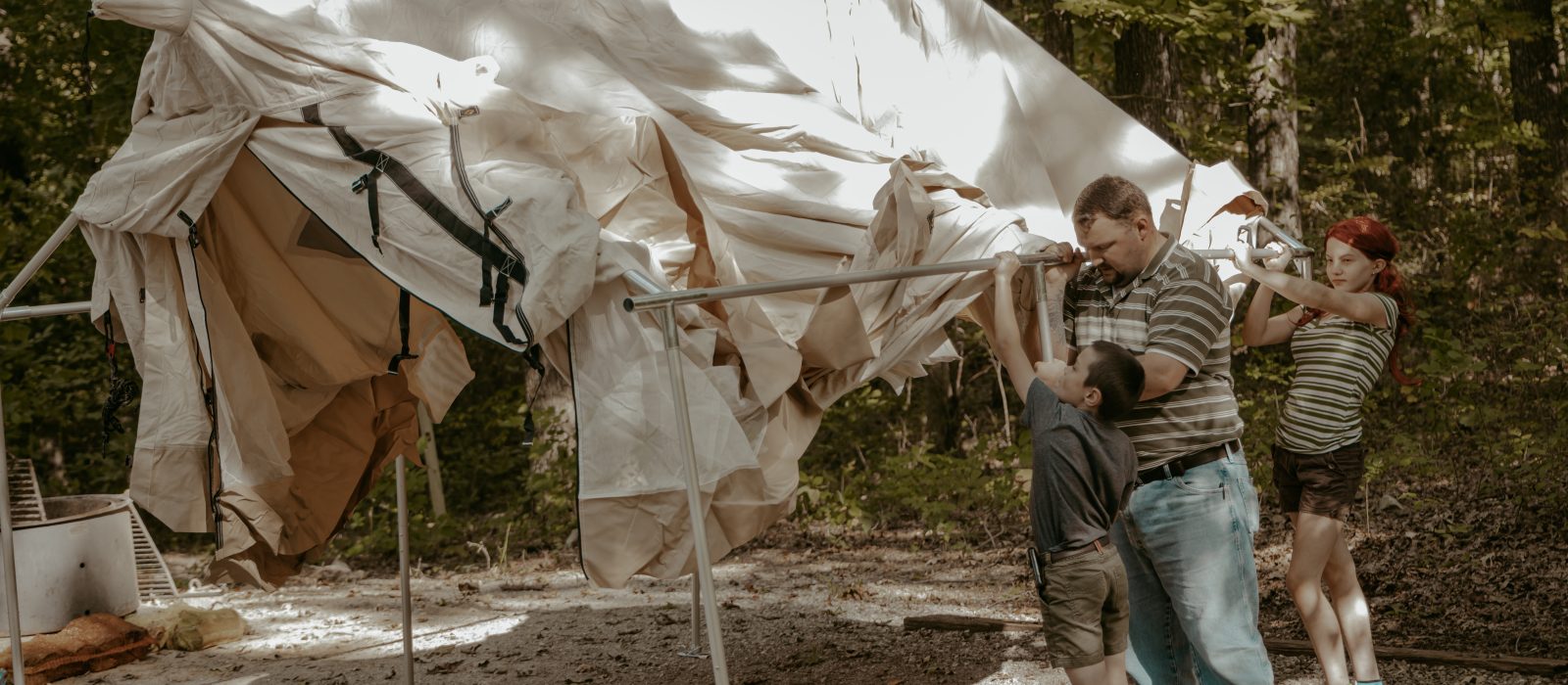 kids and father pitching a tent for family camping