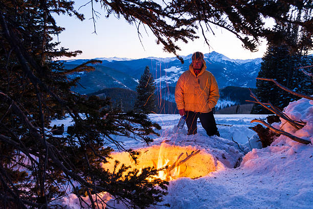 man standing in snow while enjoying campfire
