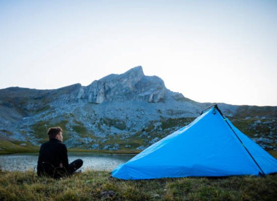 man enjoying breathtaking view of mountains during solo camping