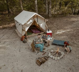 family enjoying camping by the campfire and wall tent behind