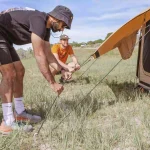 boys staking the canvas tent for camping adventure