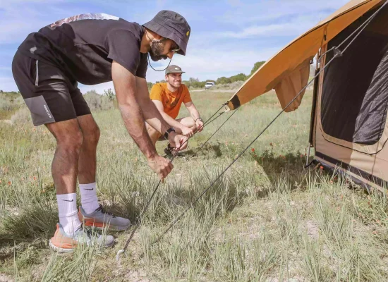 boys staking the canvas tent for camping adventure
