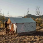 Wall tent setup for camping in nature behind mountains