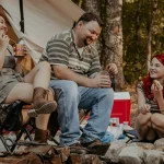 family enjoying meal on campfire during camping