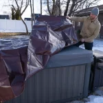 man using tarp to cover his outdoor goods