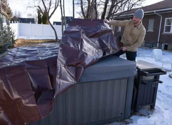 man using tarp to cover his outdoor goods