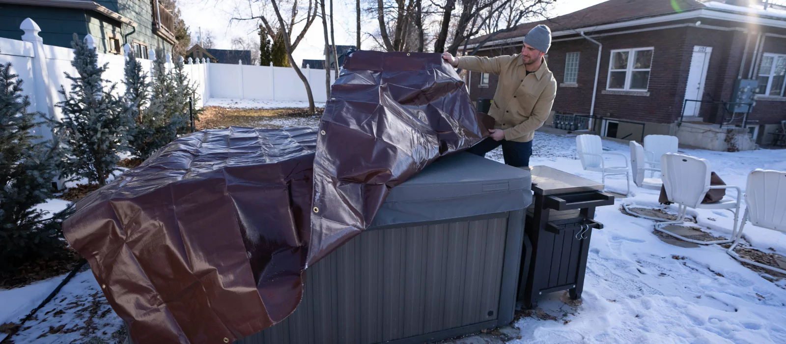 man using tarp to cover his outdoor goods