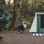 couple enjoying outdoor camping in forest with cabin tent