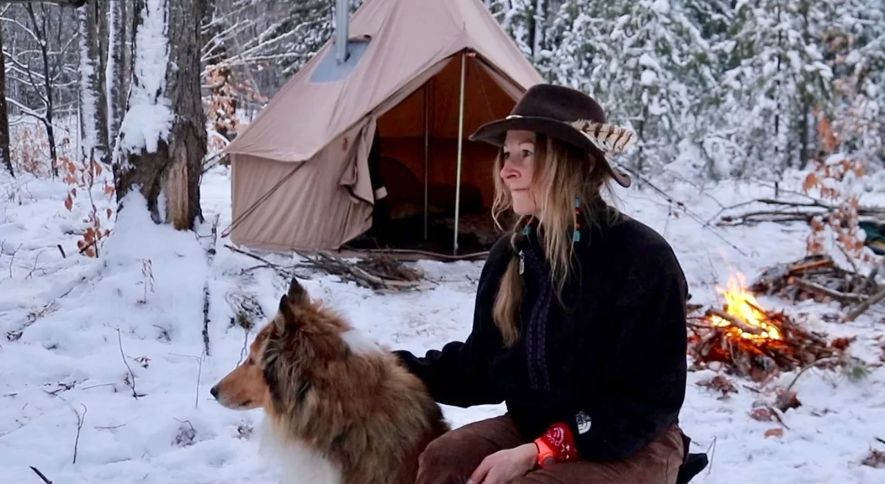 women enjoying snow camping with her dog and winter tent
