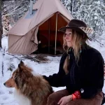 women enjoying snow camping with her dog and winter tent