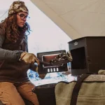 women setting up tent wood stove in canvas tent