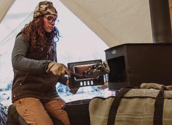 women setting up tent wood stove in canvas tent