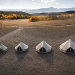 Yurt tents set up in an open field during autumn.