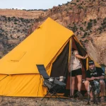 Family camping with canvas tent in rugged mountain terrain