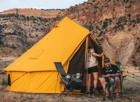 Family camping with canvas tent in rugged mountain terrain