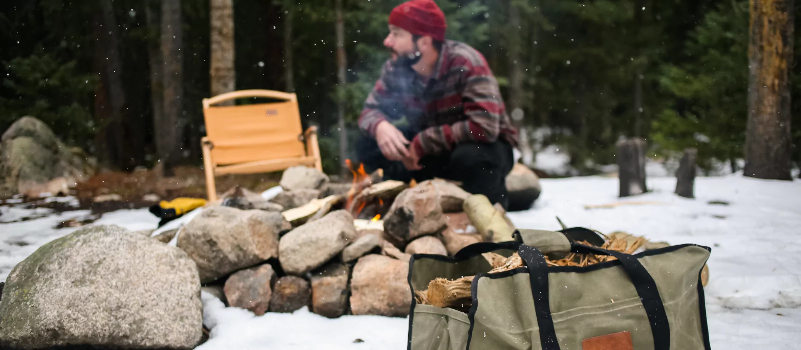 men setting up campfire with firewood carrier beside