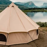 canvas tent setup near lake surrounded by mountains for outdoor adventure