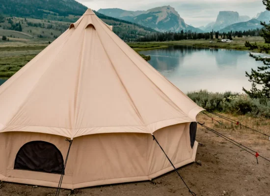 canvas tent setup near lake surrounded by mountains for outdoor adventure