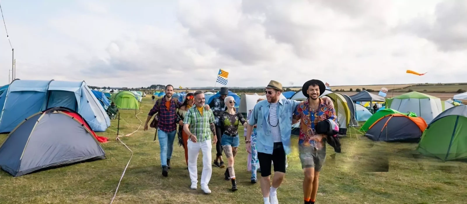 Group of friends walking through a colorful tent campsite at a California camping music festival, enjoying summer vibes and live music.