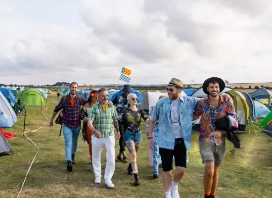 Group of friends walking through a colorful tent campsite at a California camping music festival, enjoying summer vibes and live music.