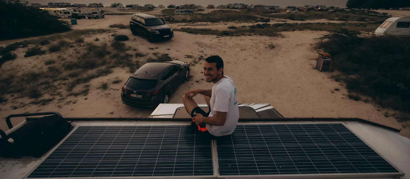 Camper enjoying off-grid beach camping with solar panels on van roof during a solar-powered camping trip.