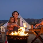 Family camping at a national park with kids around a campfire at dusk
