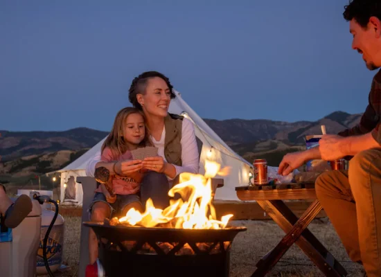 Family camping at a national park with kids around a campfire at dusk