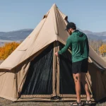 Man setting up a canvas tent in a quiet, crowd-free national park with fall foliage and mountain views