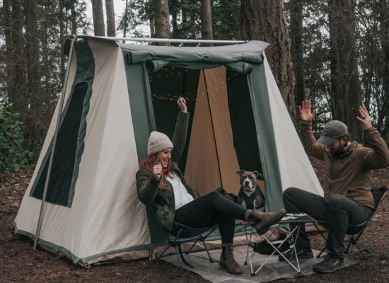 Campers dealing with common camping issues outside a canvas tent in the forest