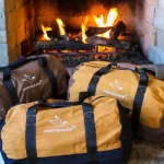 Durable canvas duffel bags perfect for camping and travel near a cozy fireplace