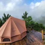 Luxury glamping tent set on a wooden deck with misty mountain views in the background