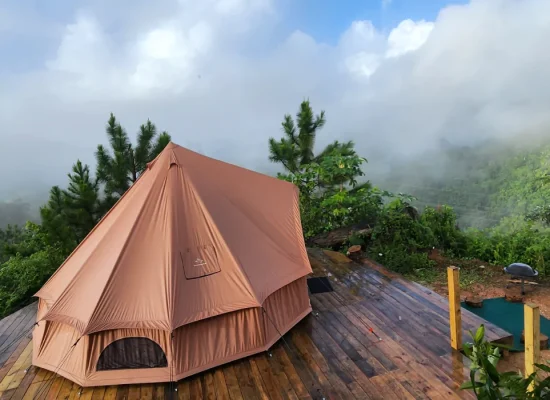 Luxury glamping tent set on a wooden deck with misty mountain views in the background