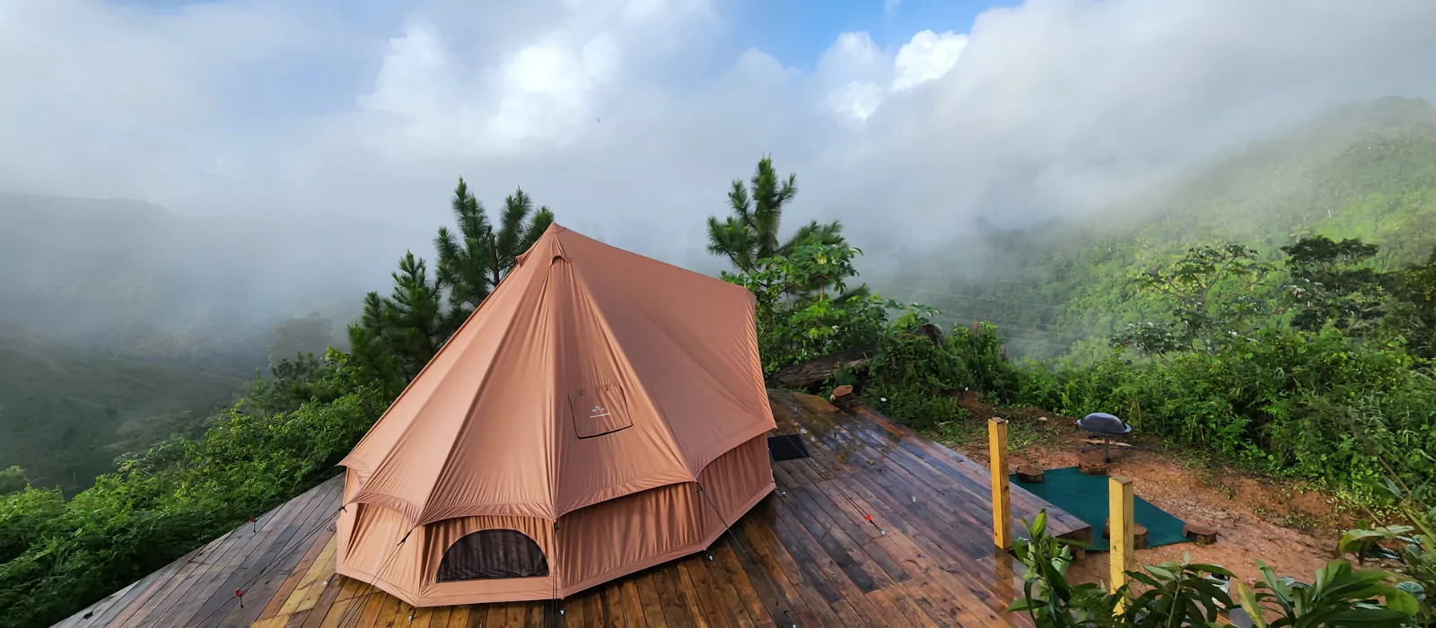 Luxury glamping tent set on a wooden deck with misty mountain views in the background