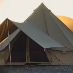 Canvas tent secured with guylines during sunset in a desert landscape