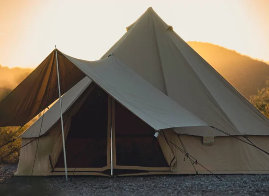 Canvas tent secured with guylines during sunset in a desert landscape