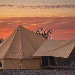 Luxury canvas tent setup in the desert at sunset, ideal for warm-weather camping and glamping adventures.