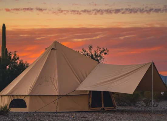 Luxury canvas tent setup in the desert at sunset, ideal for warm-weather camping and glamping adventures.