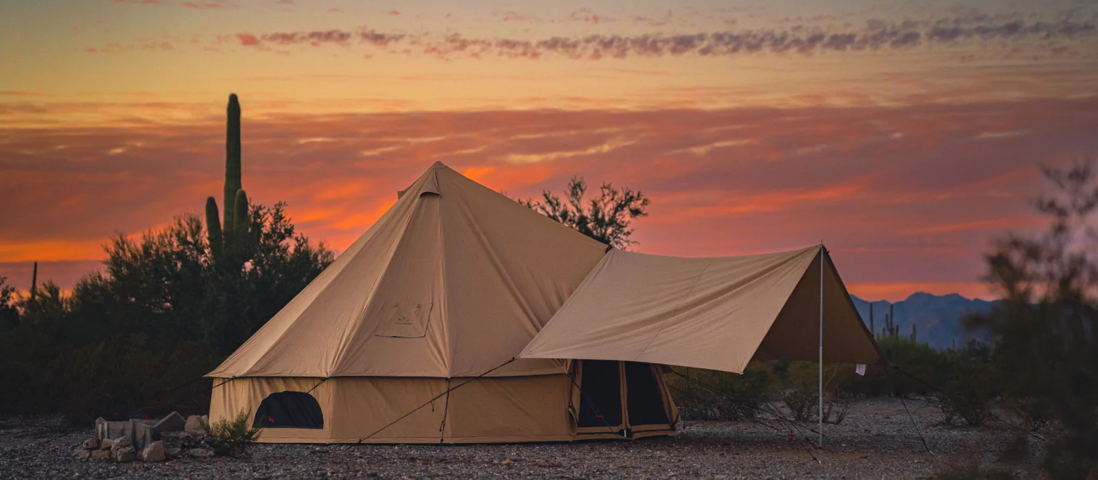 Luxury canvas tent setup in the desert at sunset, ideal for warm-weather camping and glamping adventures.