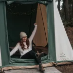 Woman stretching in the morning outside a canvas tent, ready for a restful day after a good night’s sleep while camping.