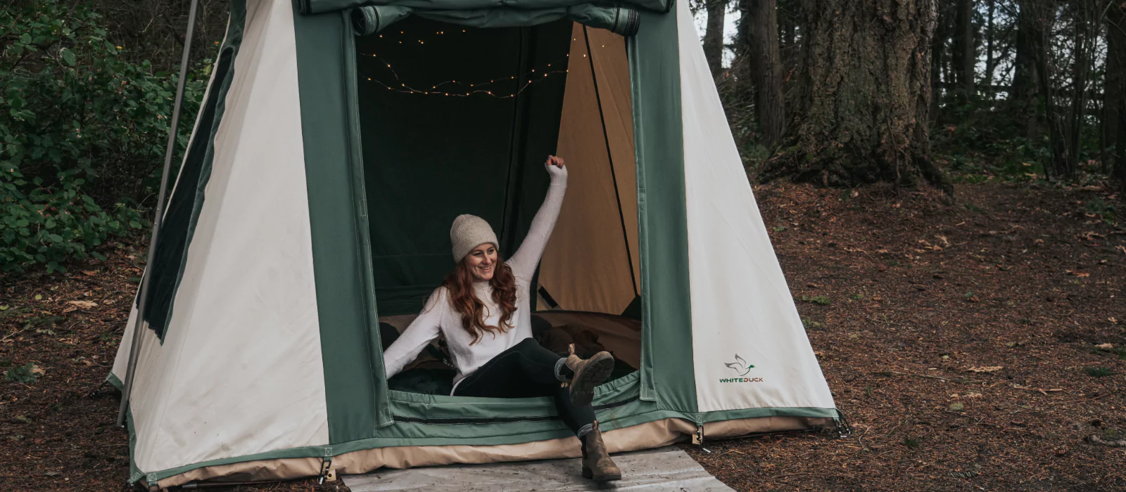 Woman stretching in the morning outside a canvas tent, ready for a restful day after a good night’s sleep while camping.