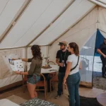 People inside a spacious wall tent with mesh screen windows, showcasing bug-free camping setup.