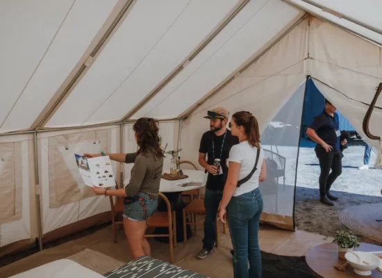 People inside a spacious wall tent with mesh screen windows, showcasing bug-free camping setup.