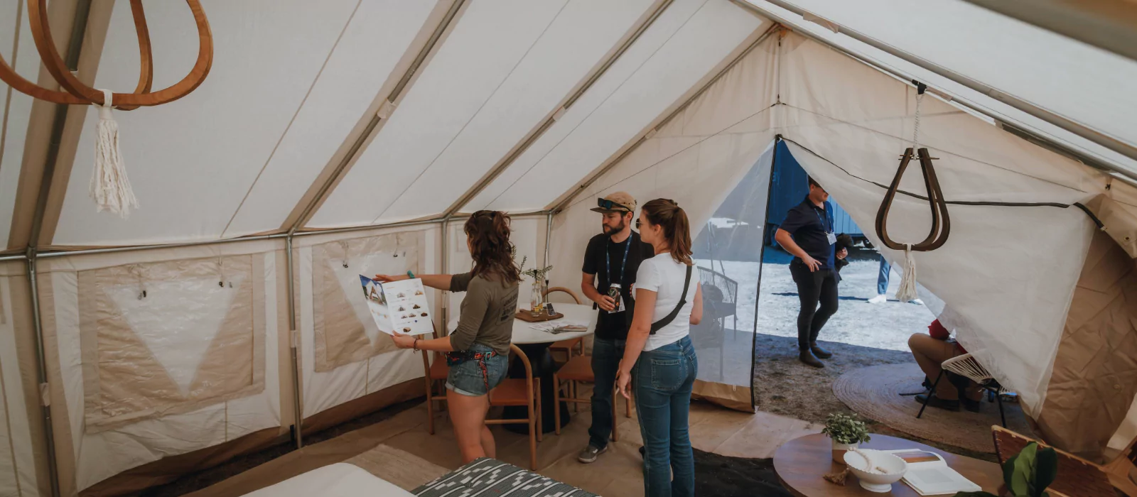 People inside a spacious wall tent with mesh screen windows, showcasing bug-free camping setup.