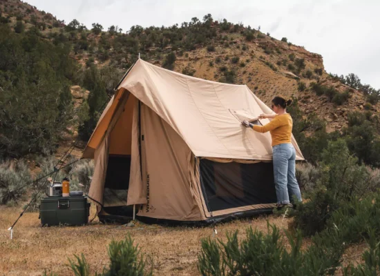 Camper setting up a canvas tent in a scenic Texas campsite surrounded by hills and greenery