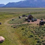 Scenic national park camping setup with tents, vehicles, and mountain views in the background