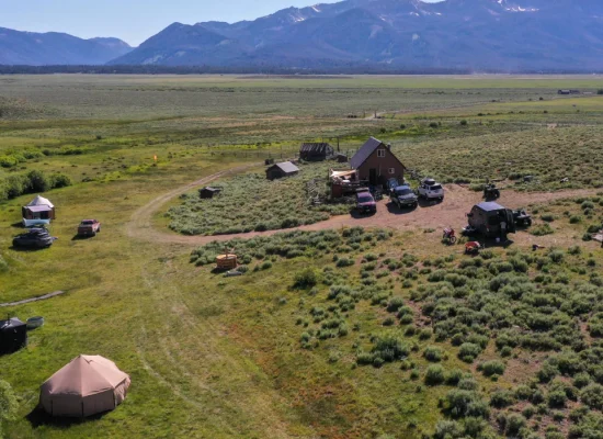 Scenic national park camping setup with tents, vehicles, and mountain views in the background
