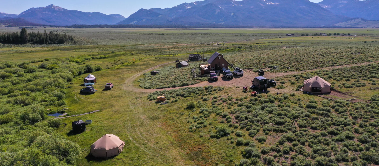 Scenic national park camping setup with tents, vehicles, and mountain views in the background